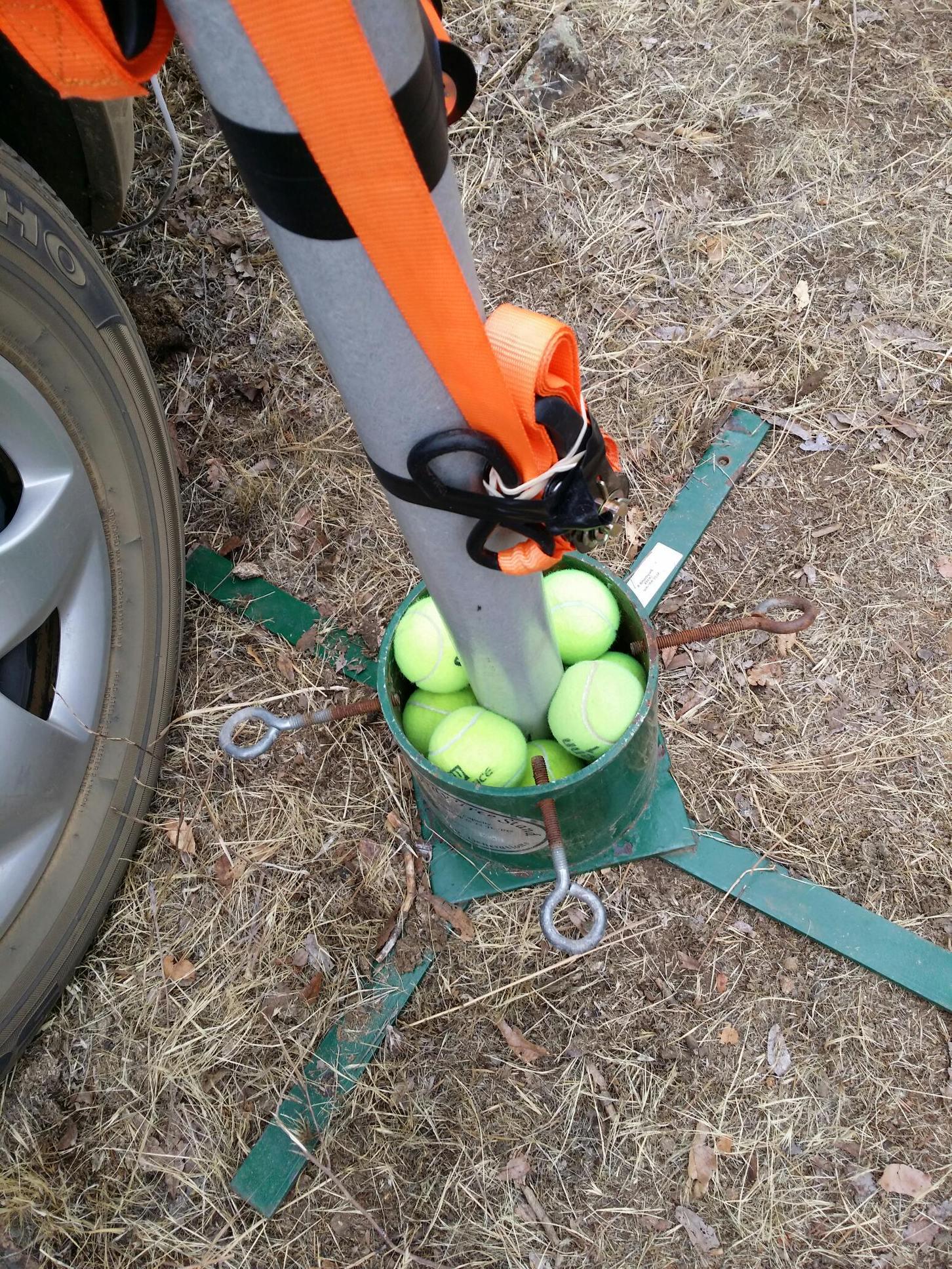 A repurposed Christmas tree stand, stuffed with tennis balls, at the base of a Yagi antenna mast