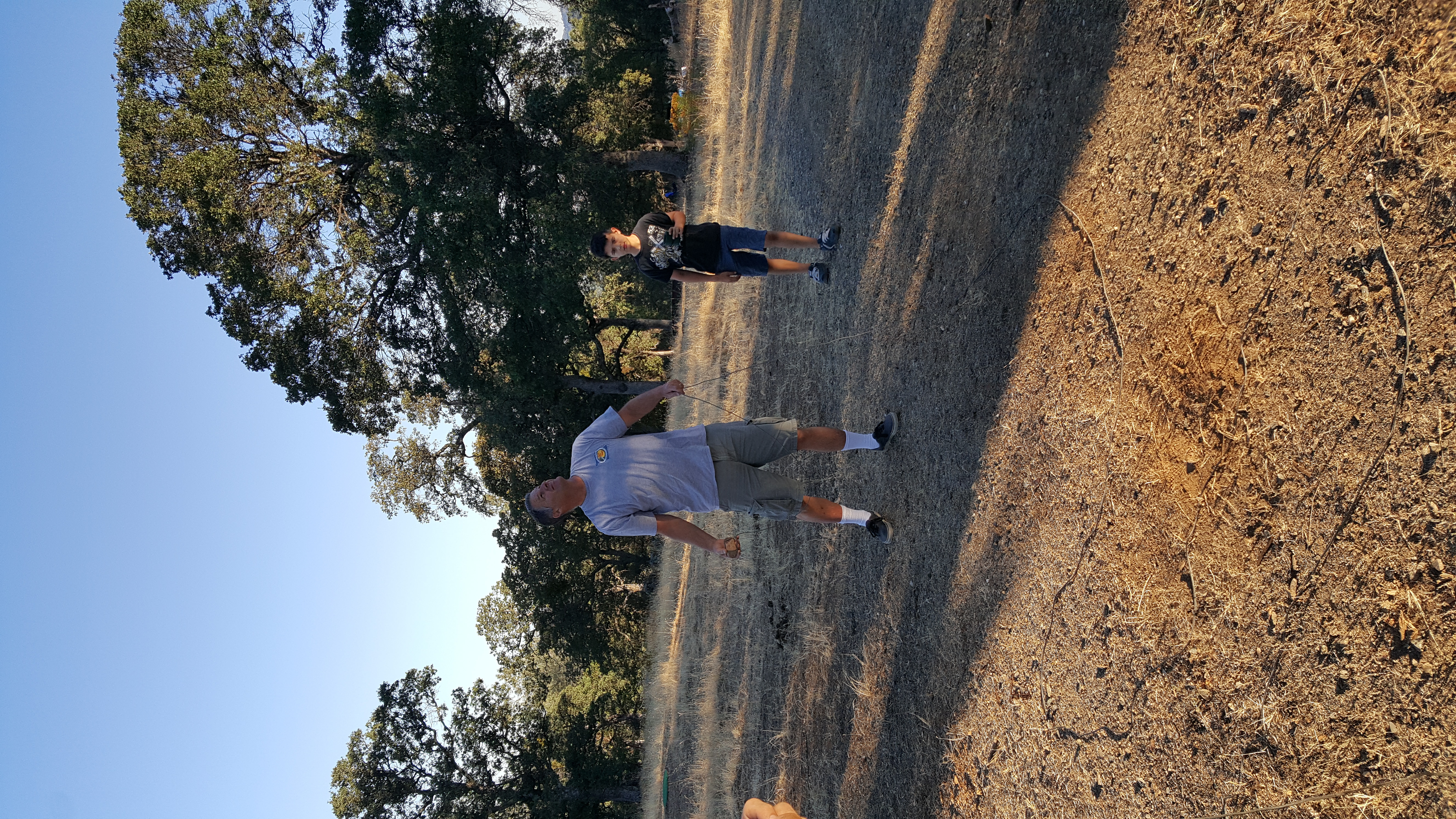 Jerry JKH prepares to heave a rock over a tree branch with a rope attached